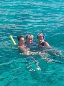 Three women snorkeling and laughing in clear ocean waters