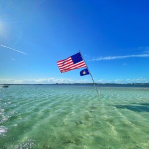 A majestic American flag proudly waving in the sea breeze on the beautiful Islamorada sandbar