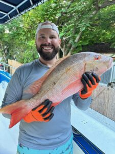 Captain Zander holding a large Mutton Snapper aboard a Lightly Salted Charters boat in Islamorada, Florida.