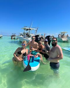 excited group of adventurers standing in shallow water next to a Lightly Salted Charters boat at the Islamorada Sandbar